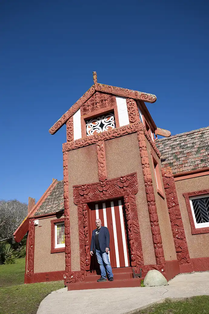 Hoani Langsbury standing on the steps at the entrance to Otakou Marae on a clear day