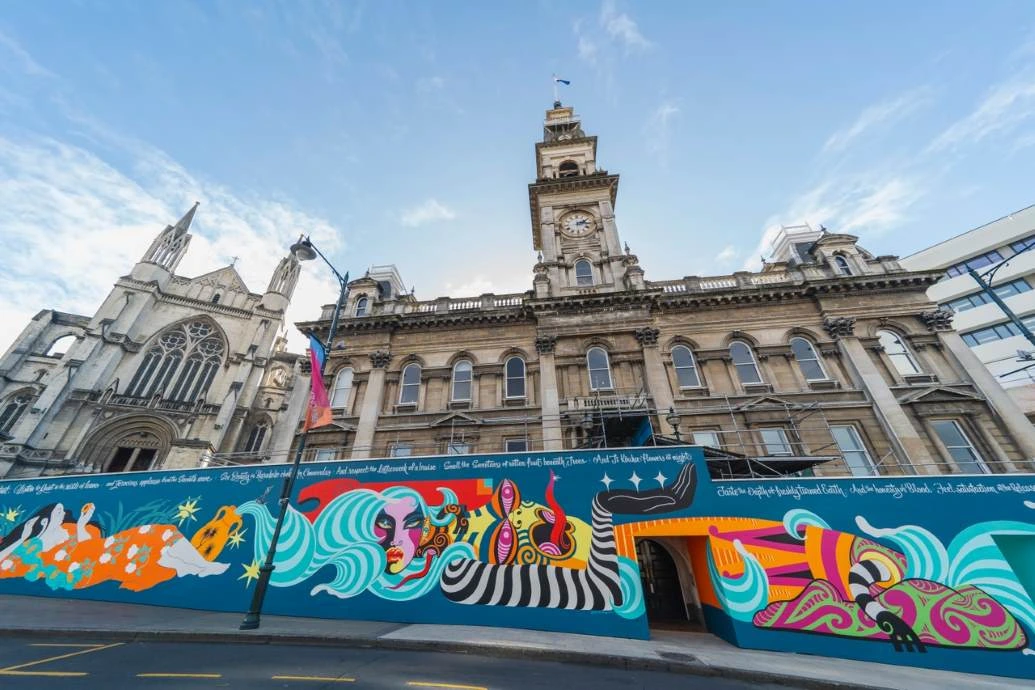 A colourful mural on hoarding wrapped around the bottom half of the Dunedin Municipal Chambers.
