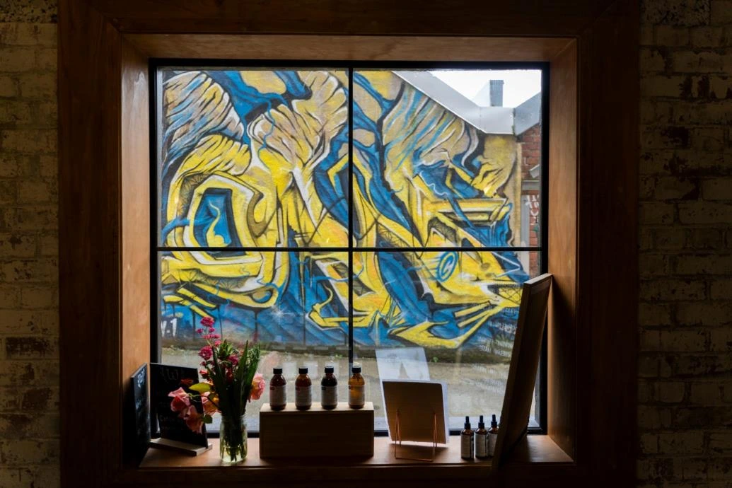 Blue and yellow street art seen through the window of Wild Dispensary.