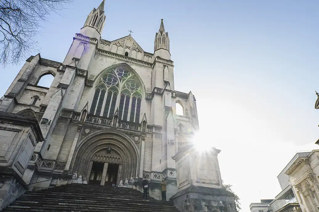 St Pauls Cathedral from the bottom of the front steps looking up to the church with the sun peaking from behind