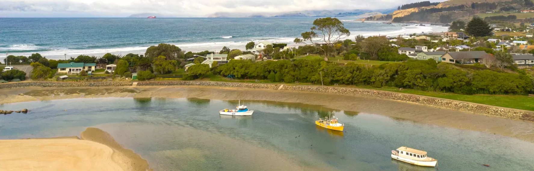 Aerial shot over boats in Waikouaiti River in Karitane, looking out to sea.