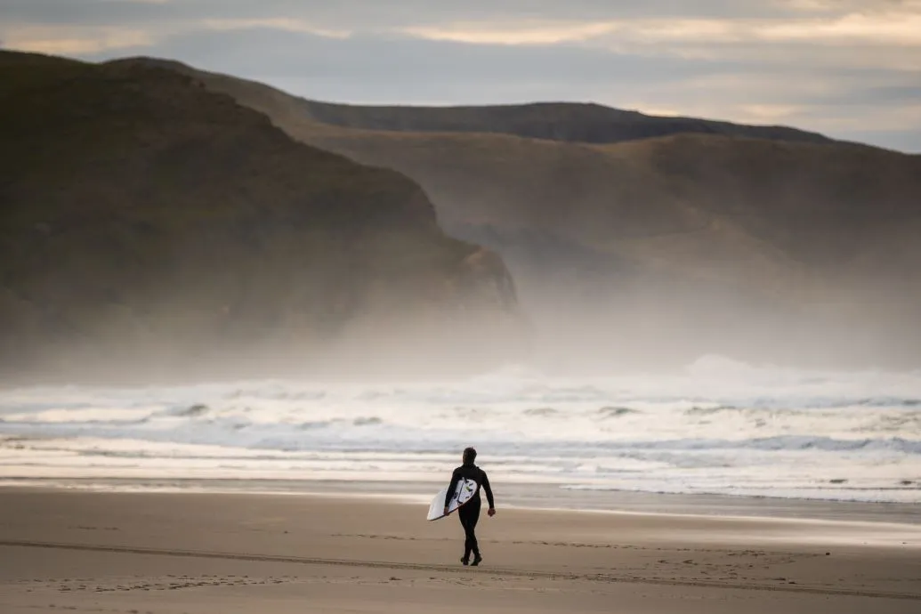 Allans Beach Surfer A surfer walks along the mist Allans Beach.