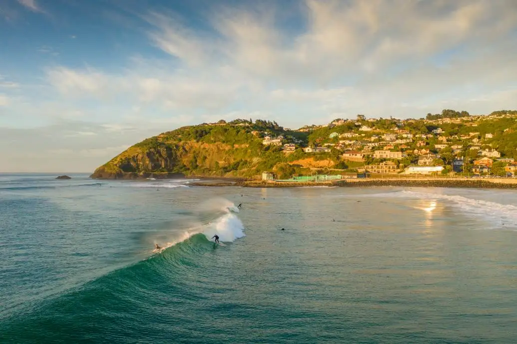 St Clair surfer morning St Clair bathed in morning sunlight with a surfer catching a wave.